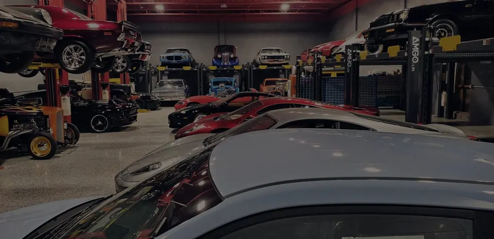 Classic and performance cars displayed on AMGO lifts inside a garage